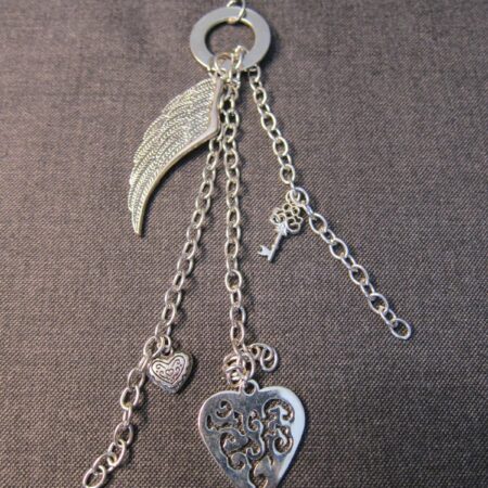 Silver tone 30" long necklace w/ feathered wing, hearts, skeleton key charms