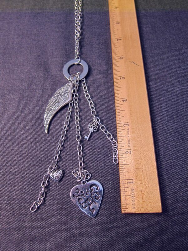 Silver tone 30" long necklace w/ feathered wing, hearts, skeleton key charms - Image 2